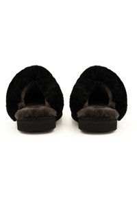 Zwarte slippers met een zachte, plush textuur, een open ontwerp aan de achterkant en een donkerbruine binnenvoering. De zolen zijn plat en zwart.