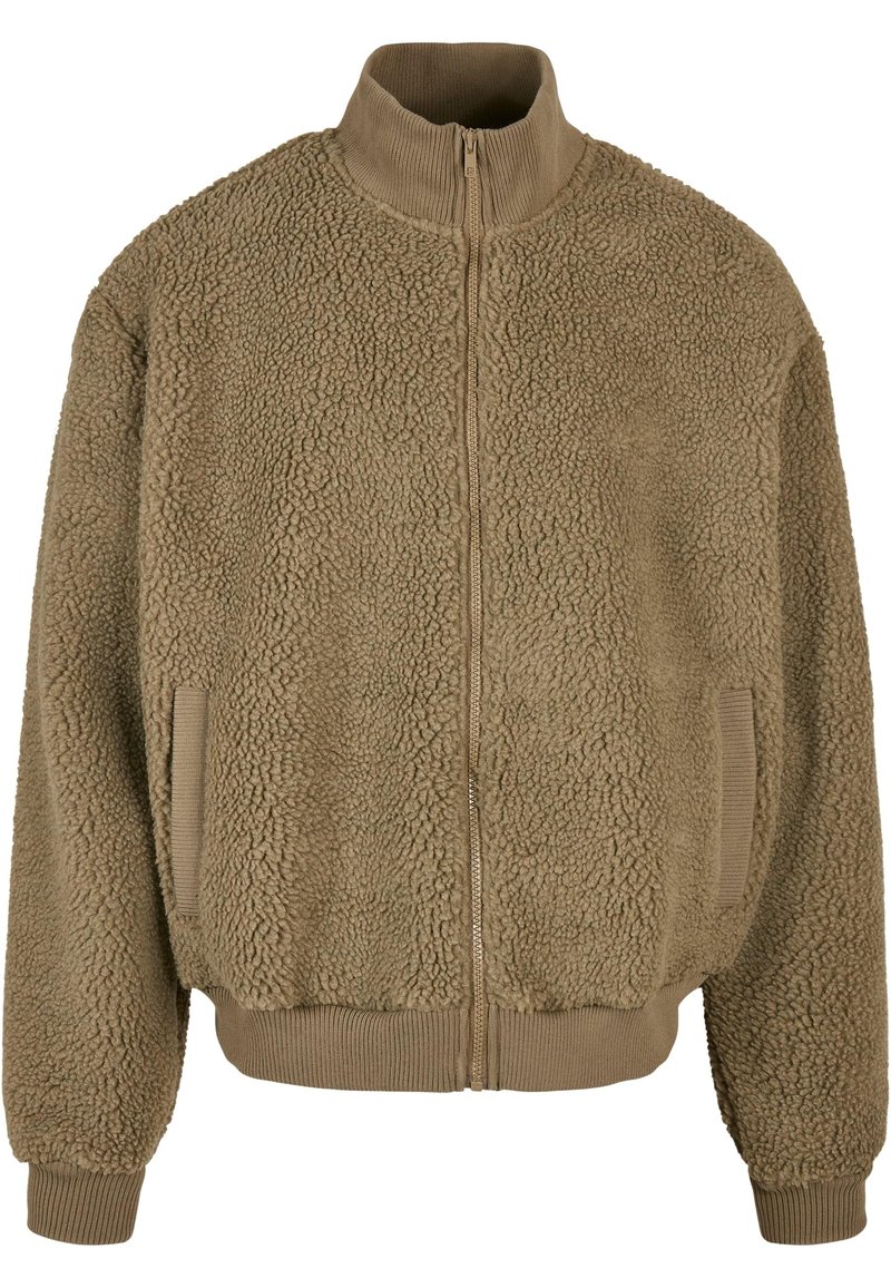 Tan zip-up jakke laget av strukturert fleece med høy krage, elastiske ermer og sidelommer. Mykt og varmt utseende.