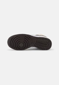 Nike sneaker sole with a black rubber bottom, circular tread patterns, and visible logo. Features a textured finish and firm structure.