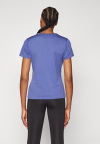 Majica z kratkimi rokavi, oprijeta, iz enobarvne vijolične tkanine, z okroglim ovratnikom in gladko teksturo; nošena s črnimi legicami.