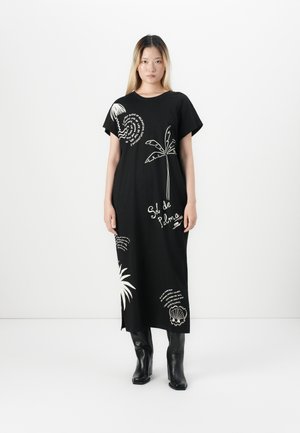 Zwarte jurk tot de knie met korte mouwen, voorzien van witte grafische ontwerpen van palmbomen en spiralen. Gemaakt van zachte stof met een losse pasvorm.