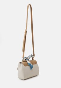 Sac bandoulière en crème et tan, avec un détail de sangle tressée et un accent de foulard bleu. Texture lisse, forme rectangulaire, sangle ajustable.