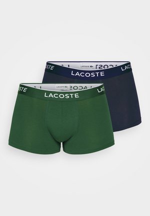 Férfi boxer alsónadrág sötétzöld és tengerészkék színben. Pamut keverék anyag, elasztikus derékpánttal, amelyen a Lacoste logó található. Sima textúra, testhez simuló forma.