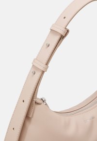 Borsa a tracolla in pelle beige con una texture liscia, tracolla regolabile, accessori in argento e un compartimento con zip. Nome del marchio impresso.