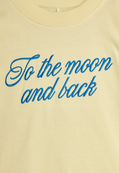 Απαλό κίτρινο φούτερ με στρογγυλή λαιμόκοψη και μπλε κεντημένο κείμενο με καλλιγραφικά γράμματα που λένε «Μέχρι το φεγγάρι και πίσω» στο μπροστινό μέρος.