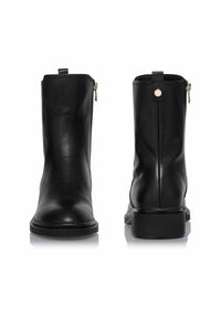 Czarne skórzane botki za kostkę o gładkiej fakturze, z bocznymi zamkami błyskawicznymi i okrągłym noskiem. Podeszwa jest niska i lekko masywna.