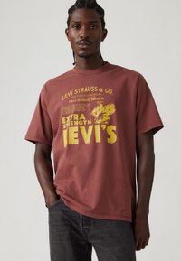 Bordeaux katoenen t-shirt met korte mouwen; voorzien van gele grafische tekst en designelementen die het Levi's merk vertegenwoordigen.