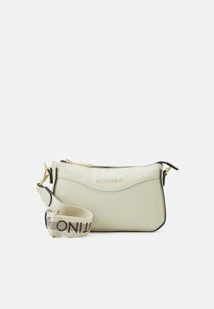 Mała jasnobeżowa skórzana torba na ramię z złotym zamkiem błyskawicznym, czarną lamówką, logo Valentino i szerokim materiałowym paskiem z czarnym napisem.