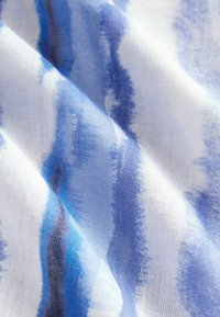 Blått och vitt tyg med ett akvarellrandmönster, som har mjuka, texturerade fibrer och en lätt, luftig känsla.