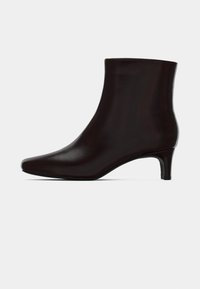 Černá kožená kotníková bota s špičatou špičkou a nízkým jehlovým podpatkem, zobrazená ve profile na jednobarevném světlém pozadí.