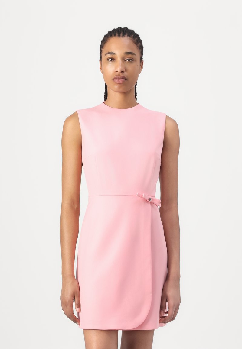 Robe sans manches rose en tissu lisse, avec une silhouette ajustée et un nœud de détail accentué à la taille.