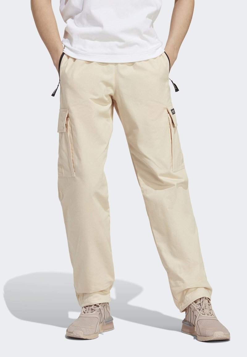Pantalones cargo beige con cintura elástica, dos bolsillos laterales y bolsillos cargo adicionales en las piernas. La tela tiene una textura suave.