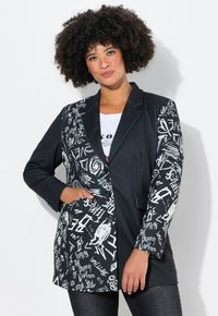 Blazer bianco e nero con un design a righe sottili e un lato in contrasto ricoperto di testo e grafiche in stile handwritten. Presenta chiusure a bottone e tasche.