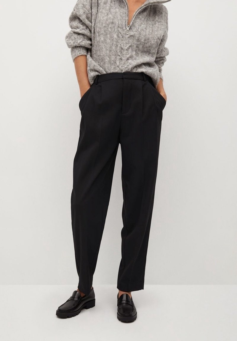 Černé kalhoty na míru s vysokým pasem, záhyby a bočními kapsami, v kombinaci se šedým texturovaným pleteným svetrem a černými mokasínami.