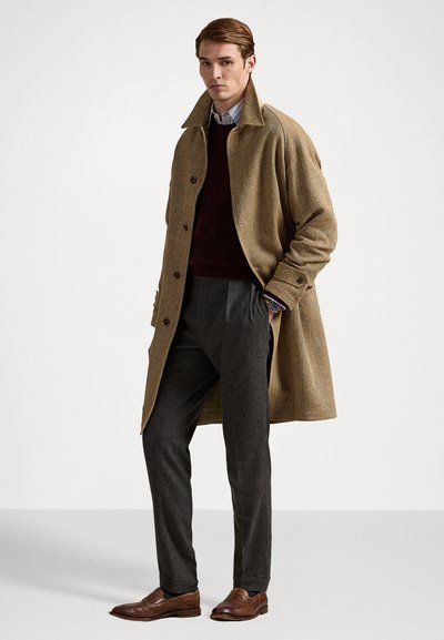 Rjava herringbone plašč z velikim ovratnikom, temno burgundska pletena jopica pod njim, sivi hlače in rjave usnjene čevlje.