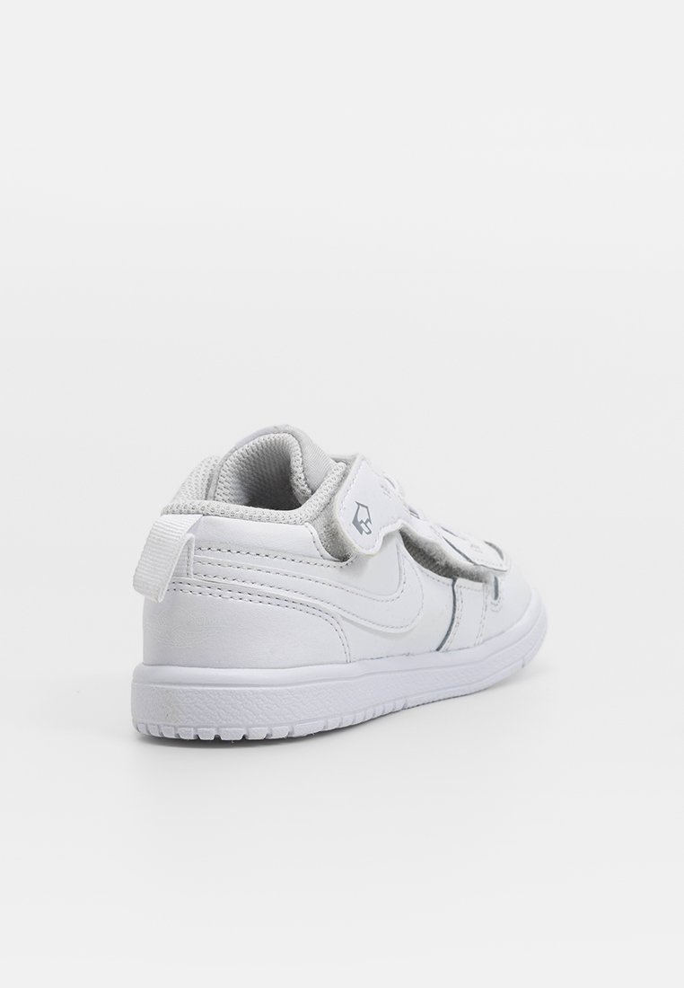 Zapatillas Nike blancas con cuero liso, diseño bajo, correa de velcro, cuello acolchado y suela de goma texturizada.