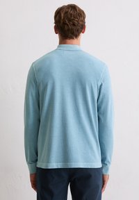 Lichtblauw poloshirt met lange mouwen van zachte stof. Voorzien van een kraag, knoopsluiting en een regular fit met een rechte zoom.