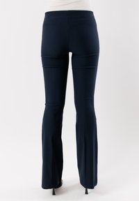Pantaloni svasati blu navy realizzati in un tessuto elasticizzato, con una vita alta e una texture liscia. La vista posteriore mostra una finitura pulita senza tasche.