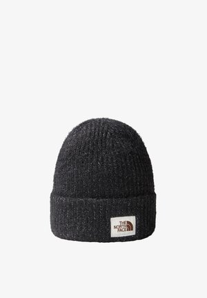 Czarna dziergana czapka beanie z podwiniętym brzegiem, z białą naszywką z brązowym logo z przodu, wykonana z miękkiego, teksturowanego materiału.