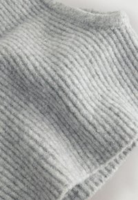 Un tissu tricoté gris doux avec une texture côtelée, présentant des rayures alternées claires et foncées sur la surface.