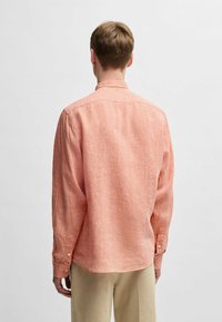 Camicia a maniche lunghe in lino corallo chiaro. Presenta un colletto classico, polsini con bottone e una vestibilità rilassata con una sottile trama.