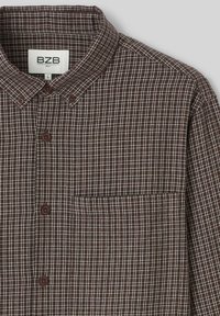 Chemise à carreaux brune avec motif de grille blanche, col, bouton devant, poche poitrine unique et tissu texturé. Étiquette de marque : BZB, taille L.