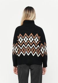 Schwarzer Pullover mit Rollkragen, der ein Zickzackmuster in Braun, Weiß und Schwarz zeigt. Lässige Passform und strukturierter Strick.