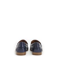 Mocasines de cuero azul marino con un acabado suave, puntera redonda y un bajo tacón de madera; presentan costuras sutiles y un diseño de parte trasera contorneada.