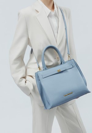 Struktureret håndtaske i tekstureret lyseblåt læder med korte håndtag, en aftagelig rem og en guldfarvet logoaccent foran.