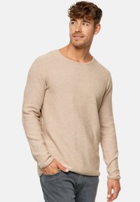 Beige pitkähihaine neulepusero, jossa on pyöreä kaula-aukko, valmistettu teksturoidusta kankaasta, rento malli ja hienovarainen heather-kuvio.