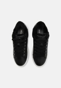 Juodi odiniai sportiniai bateliai su storais juodais raišteliais ir pūkuotu juodu kailiu viduje, derinami su baltais gumos padu, matomi iš viršaus.