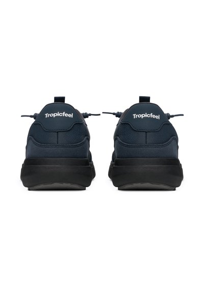 Par de zapatillas Tropicfeel de color azul oscuro vistas desde atrás con suelas negras y tiradores sobre un fondo blanco.