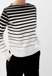 Svart och vit randig långärmad topp med båtutskärning, tillverkad av mjukt tyg, med en avslappnad passform och en enfärgad vit nederdel.