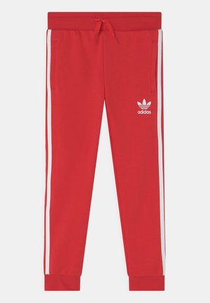 Czerwone spodnie dresowe Adidas z białymi paskami po bokach, elastyczną talią ze sznurkiem, przednimi kieszeniami i logo Adidas na lewym udzie.
