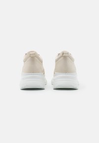 Baskets beiges avec une tige en cuir lisse et une semelle blanche épaisse. Dotées d'un col rembourré et d'une languette de tirage à l'arrière pour un enfilage facile.