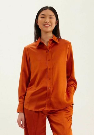 Chemise en satin de couleur orange vif avec un devant boutonné, un col, des manches longues et une coupe décontractée, assortie à un pantalon matching.