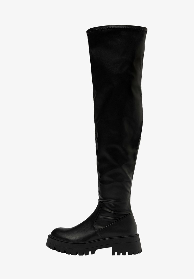 Bottes noires montant jusqu'aux genoux avec une finition en cuir lisse, semelle en caoutchouc épaisse et design plat. Texture lisse et accents matériels minimalistes.