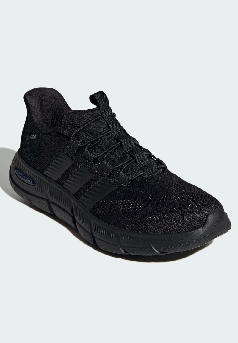 Chaussure de sport noire avec une tige en mesh texturé, fermeture à lacets et une semelle en caoutchouc dotée d'un design robuste et d'une semelle intermédiaire flexible.