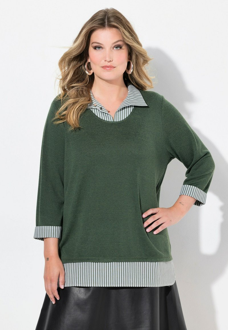 Maglia verde a maniche lunghe con colletto a righe e dettagli a righe nei polsini. Vestibilità ampia, tessuto testurizzato e orlo a righe in contrasto.