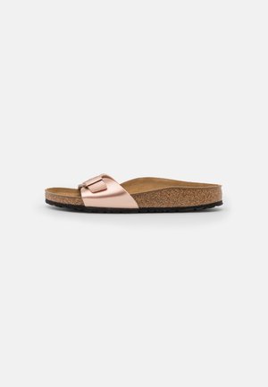 Sandal med spenne i metallisk rosegull, korkfotbelegg og teksturert svart gummisåle. Lavprofil design med en minimalistisk spændeaccent.