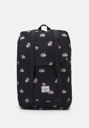 Zaino nero a fiori con fiori rosa, materiale in tessuto, chiusura con patta, due spallacci neri, tasca frontale e una toppa con il logo nella parte inferiore.