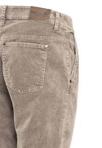 Vue arrière d'un jean beige avec une poche arrière unique et un patch en cuir marron portant la marque Pulz Jeans sur la ceinture.