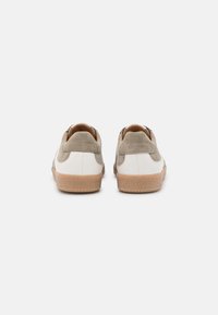 Sneakers con parte superiore in pelle bianca e accenti in camoscio grigio, con suola in gomma color beige. Il design del tallone è arrotondato e presenta una superficie testurizzata.