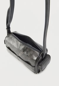 Μαύρη δερμάτινη τσάντα ώμου με δομημένο ορθογώνιο σχήμα, κλείσιμο με φερμουάρ, λεία εξωτερική επιφάνεια και επίπεδο λουρί. Ορατές λεπτομέρειες ραφής.