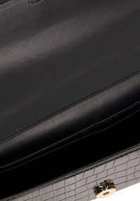 Black faux leather purse with a crocodile texture and gold hardware. The interior is smooth and unadorned, featuring a single compartment.