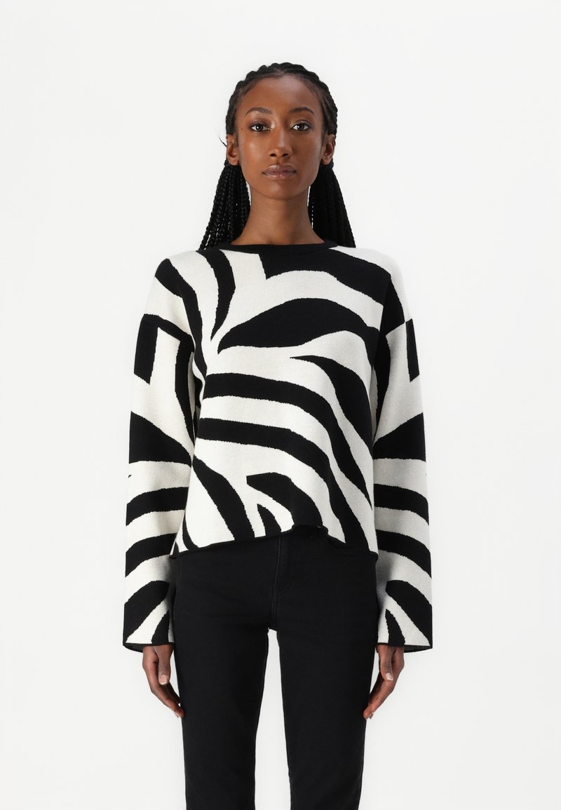 Mustavalkoruudullinen neulepaita, jossa on pitkät hihat, pyöreä pääntie ja reilu istuvuus, valmistettu pehmeästä neulosmateriaalista.