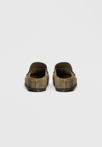 Olivgrüne Wildleder-Lite mit niedrigem Profil, offenem Rücken und strukturiertem Gummisohle. Mit einfacher Naht und minimalistischem Design.