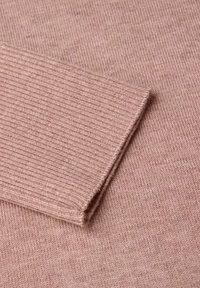 Hellbrauner gerippter Stoff mit einer glatten Textur. Zwei überlappende Stücke zeigen subtile Variationen im Rippmuster.