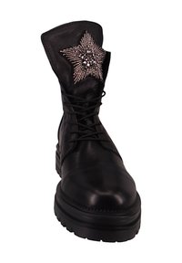 Botín de cuero negro con suela plana, diseño con cordones y un adorno en forma de estrella con cuentas plateadas en la parte superior.
