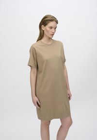 Krótkosleeve'owa, beżowa sukienka z bawełny o luźnym kroju, okrągłym dekolcie i prostym fasonie, sięgająca nad kolano. Gładka tekstura.